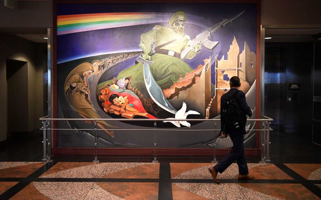 : Un voyageur regarde par-dessus une fresque murale, faisant partie d'une installation à l'aéroport international de Denver intitulée, Children of the World Dream Peace 20 octobre 2016.