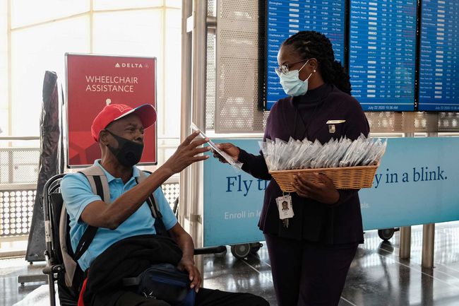 Un employé de Delta Airline donne un masque facial à un passager lors de l'enregistrement à l'aéroport national Ronald Reagan