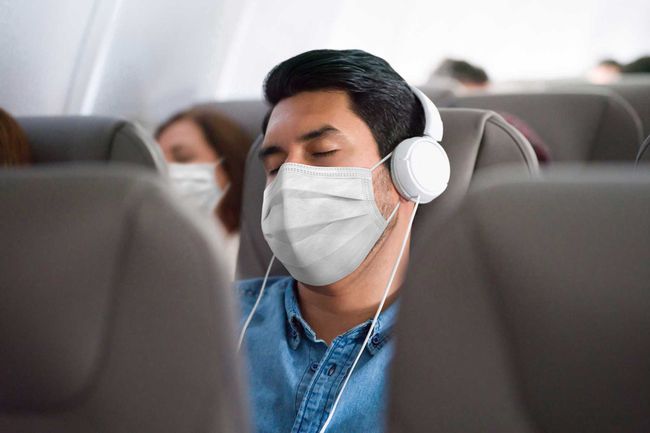 Homme voyageant et dormant dans l'avion portant un masque facial
