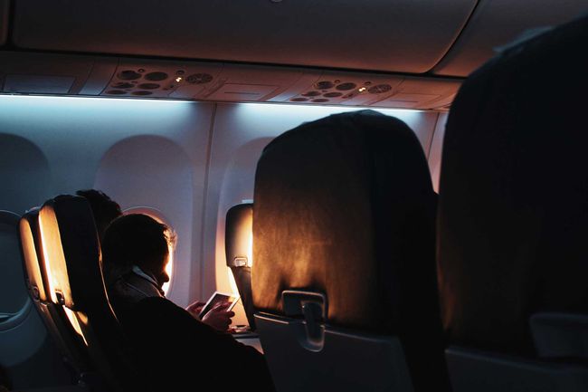 Passager dormant dans un avion faiblement éclairé avec le soleil entrant par les fenêtres