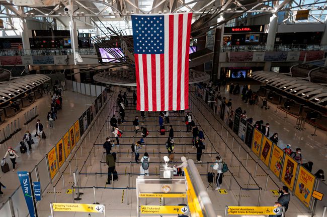 Les passagers, certains portant des masques et des équipements de protection, font la queue pour leur vol au terminal 1 de l'aéroport John F. Kennedy (JFK) au milieu de la nouvelle pandémie de coronavirus le 13 mai 2020