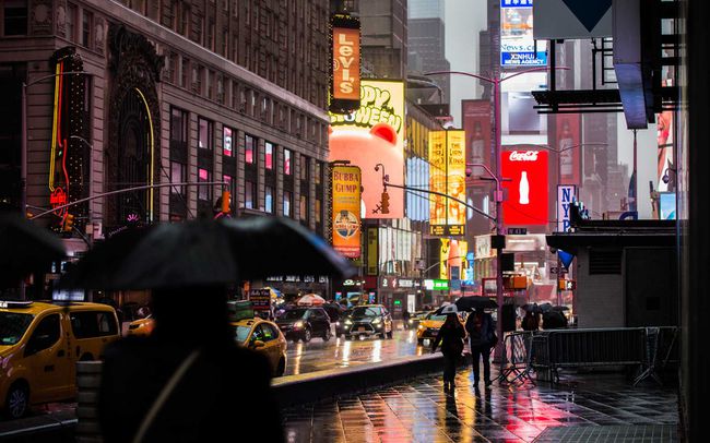 Touristes et voitures à Times Square la nuit pendant un jour de pluie.
