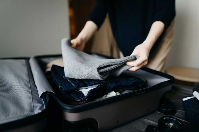 Femme emballant une valise sur le lit pour un voyage à la maison