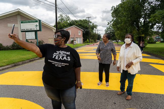 Les gens sortent pour voir "Black Towns Matter" qui est peint dans une rue le 19 juin 2020 à Houston, Texas.