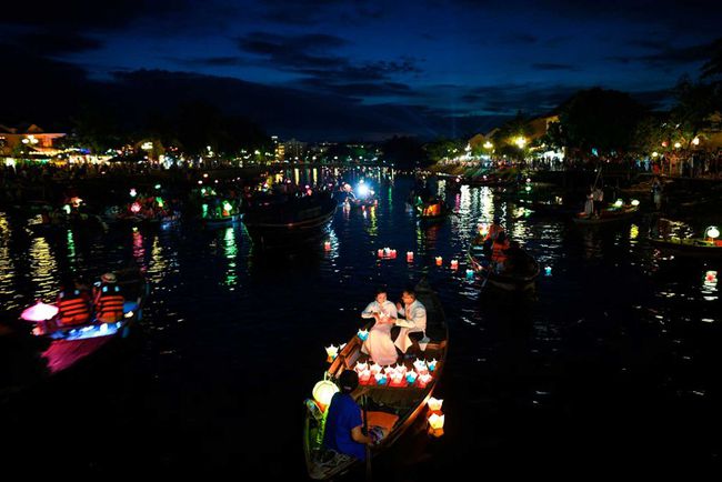 Les gens font un tour sur des bateaux au crépuscule pour libérer des lanternes en papier pour la bonne chance pendant le festival de la mi-automne sur la rivière Thu Bon