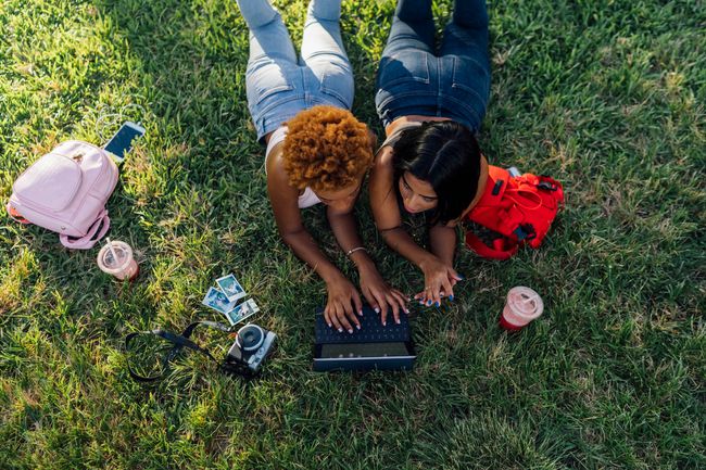 Deux amis se détendant dans un parc à l'aide d'une tablette