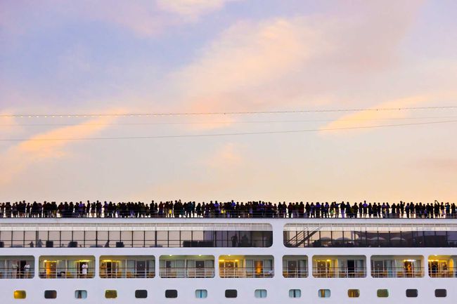 Passagers sur les ponts supérieurs d'un bateau de croisière au coucher du soleil