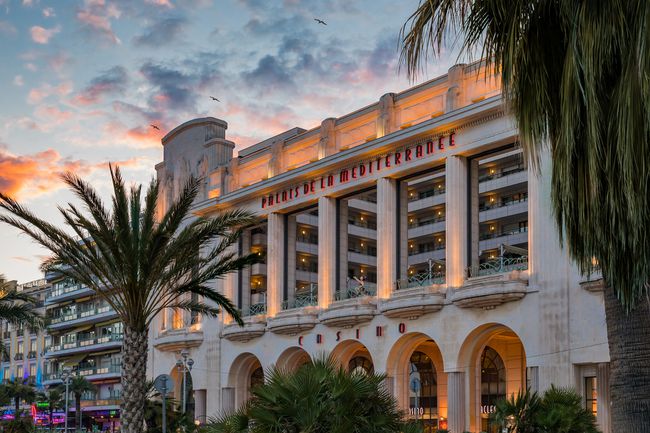 Palmiers et le célèbre Palais de la Méditerranée Art Deco hotel and casino by Hyatt sur la Promenade des Anglais au coucher du soleil