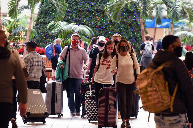 Les voyageurs portant des masques faciaux arrivent à l'aéroport international d'Orlando la veille de Noël