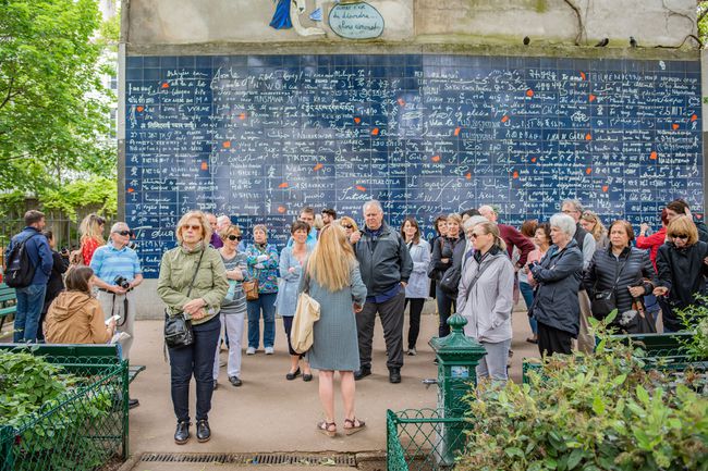 Les gens d'un grand groupe de touristes s'arrêtent pour voir le célèbre mur mural Je t'aime, une attraction touristique populaire dans le quartier de Montmartre.