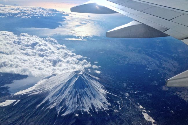 Vue sur le mont Fuji enneigé depuis un avion volant avec une aile au loin de la fenêtre