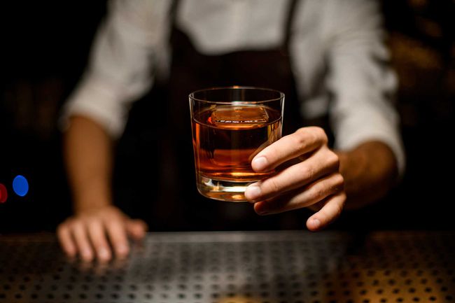 Barman professionnel servant un cocktail dans le verre avec un gros glaçon
