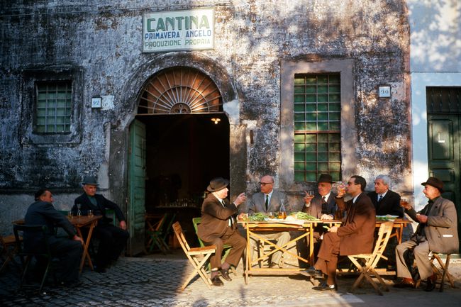 Les personnes âgées assis à des tables à l'extérieur d'une taverne en Italie