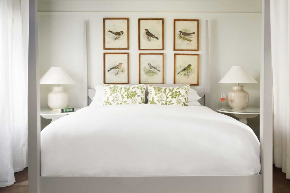 Une chambre verte et blanche, avec des peintures d'oiseaux au-dessus du lit, au Farmhouse Inn