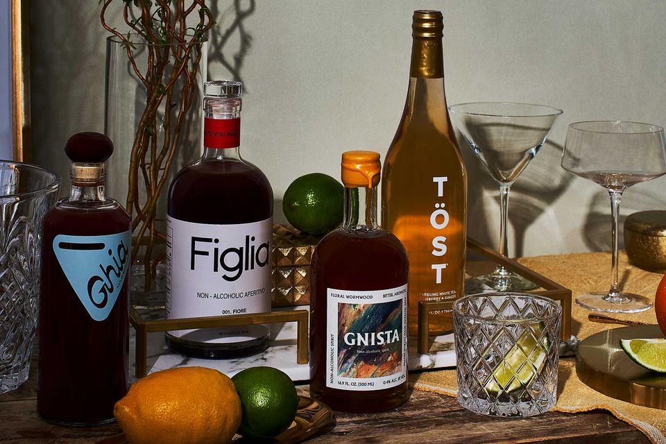 Table de bar à domicile montrant quatre bouteilles de spiritueux sans alcool, des verres, un citron et des limes