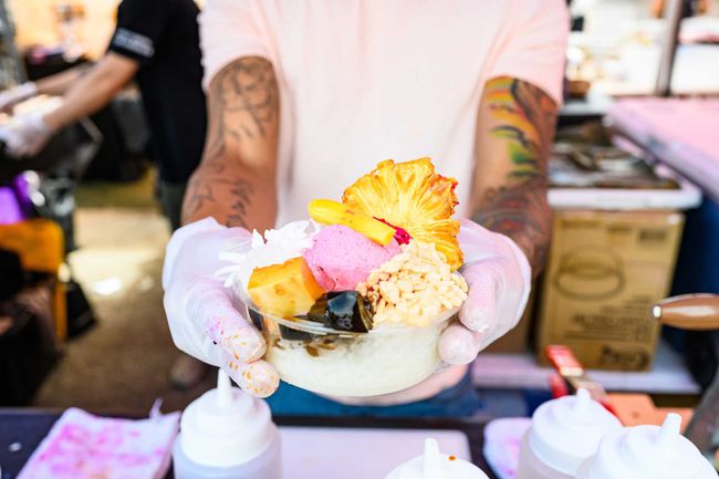 À New York, aux États-Unis, un vendeur de nourriture en activité portant des gants de protection montre un dessert philippin fraîchement préparé lors de l'événement gastronomique de Smorgasburg.