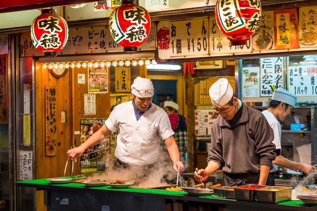 Des hommes préparent des plats de rue traditionnels japonais à Osaka, au Japon.