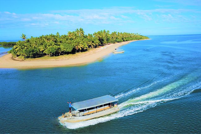Un bateau de transport passant devant Likuri Island Resort à Fidji