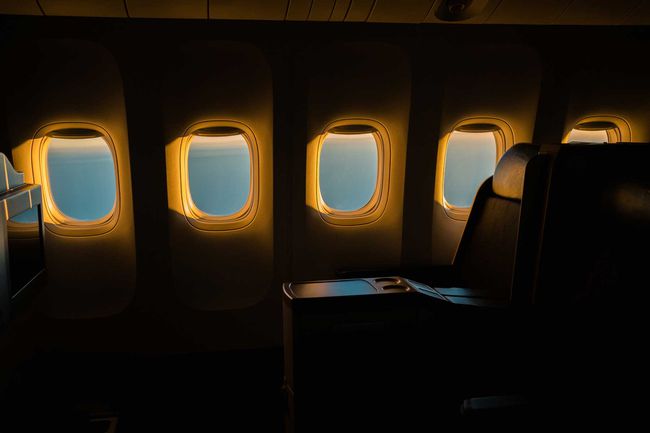 Rangée de fenêtres d'avion pendant l'heure d'or dans une section de première classe de cabine d'avion