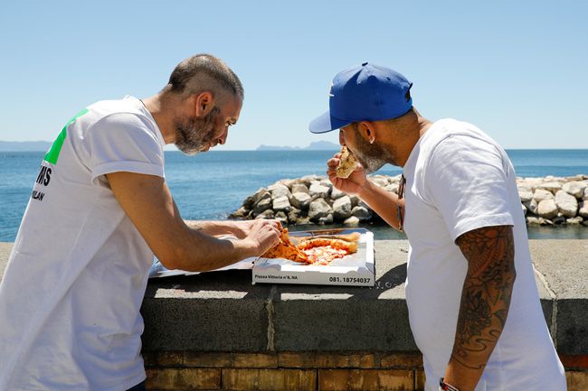 Deux hommes mangent une pizza sur le front de mer à Naples