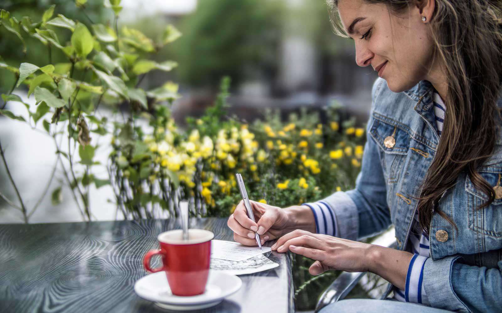 Pays-bas, Amsterdam, femme écrivant des cartes postales dans un café de la rue