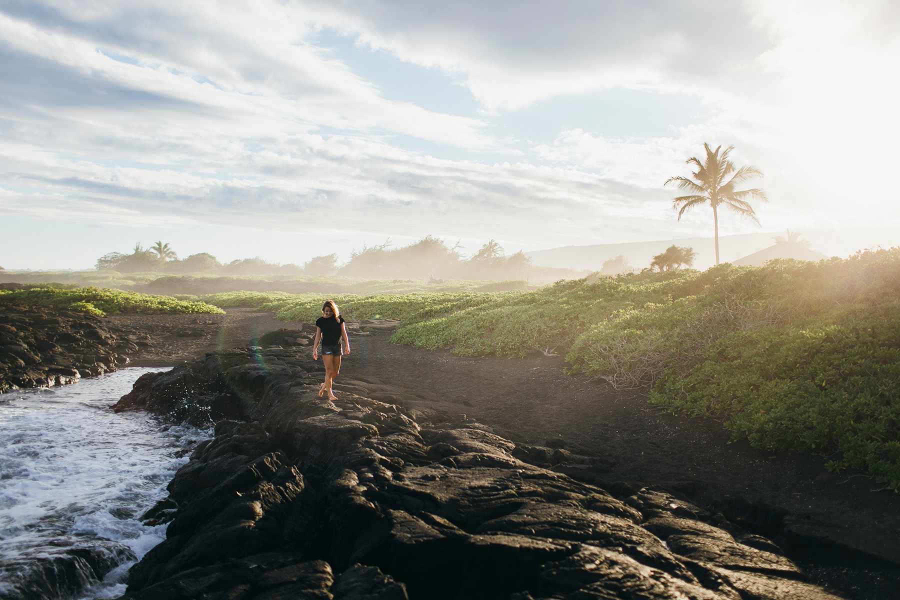 Une personne marche sur des roches de lave près de l'océan, Big Island, Hawaii.