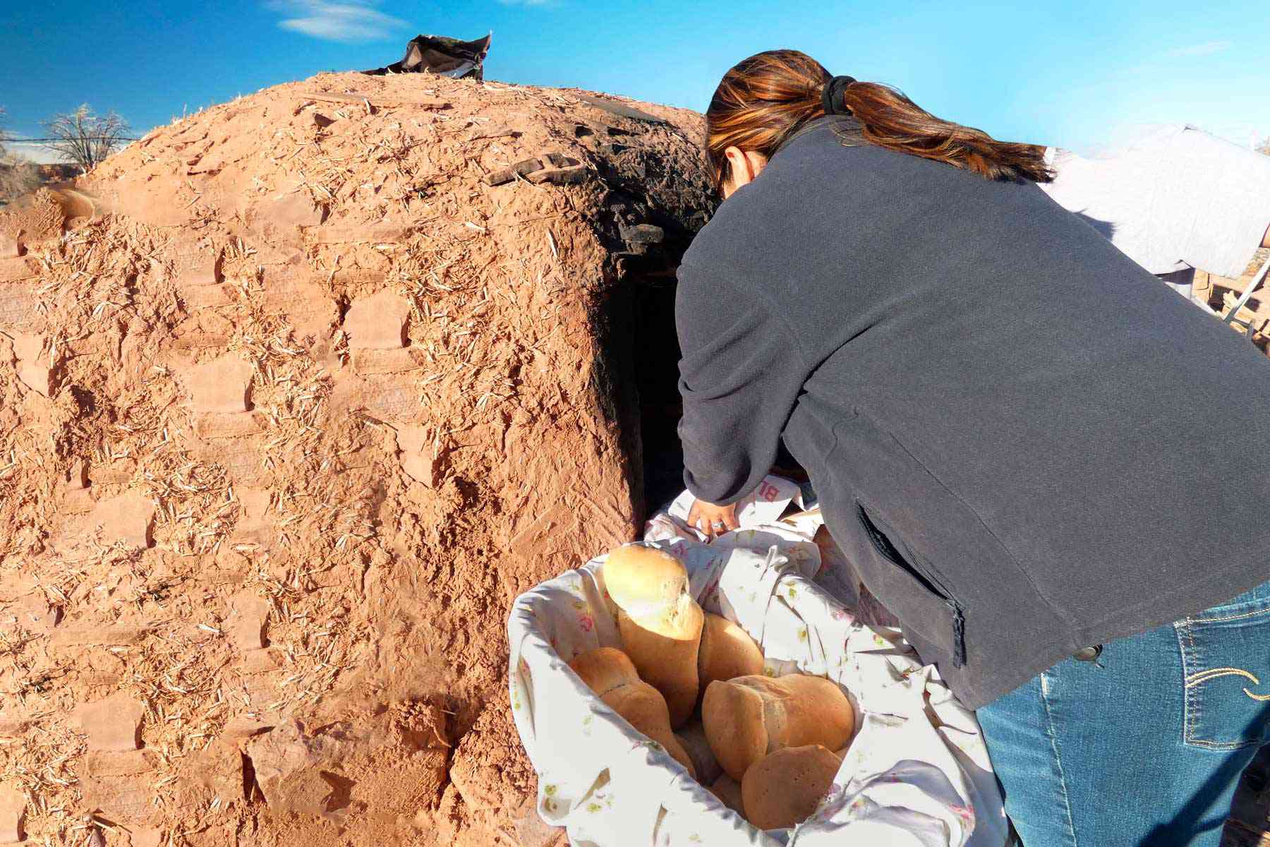 Une femme faisant du pain Zuni traditionnel dans un four fabriqué à partir de la terre
