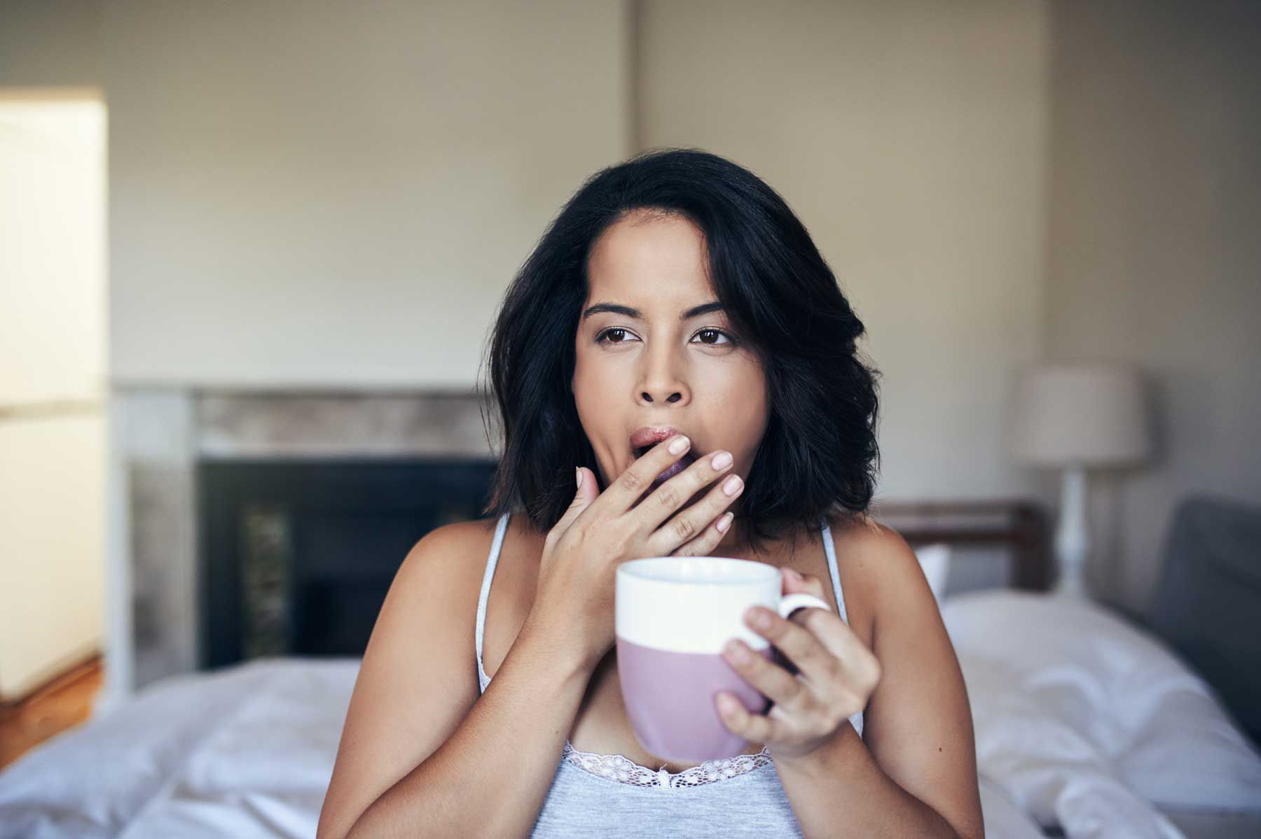 Photo d'une jeune femme bâillant en prenant un café le matin à la maison