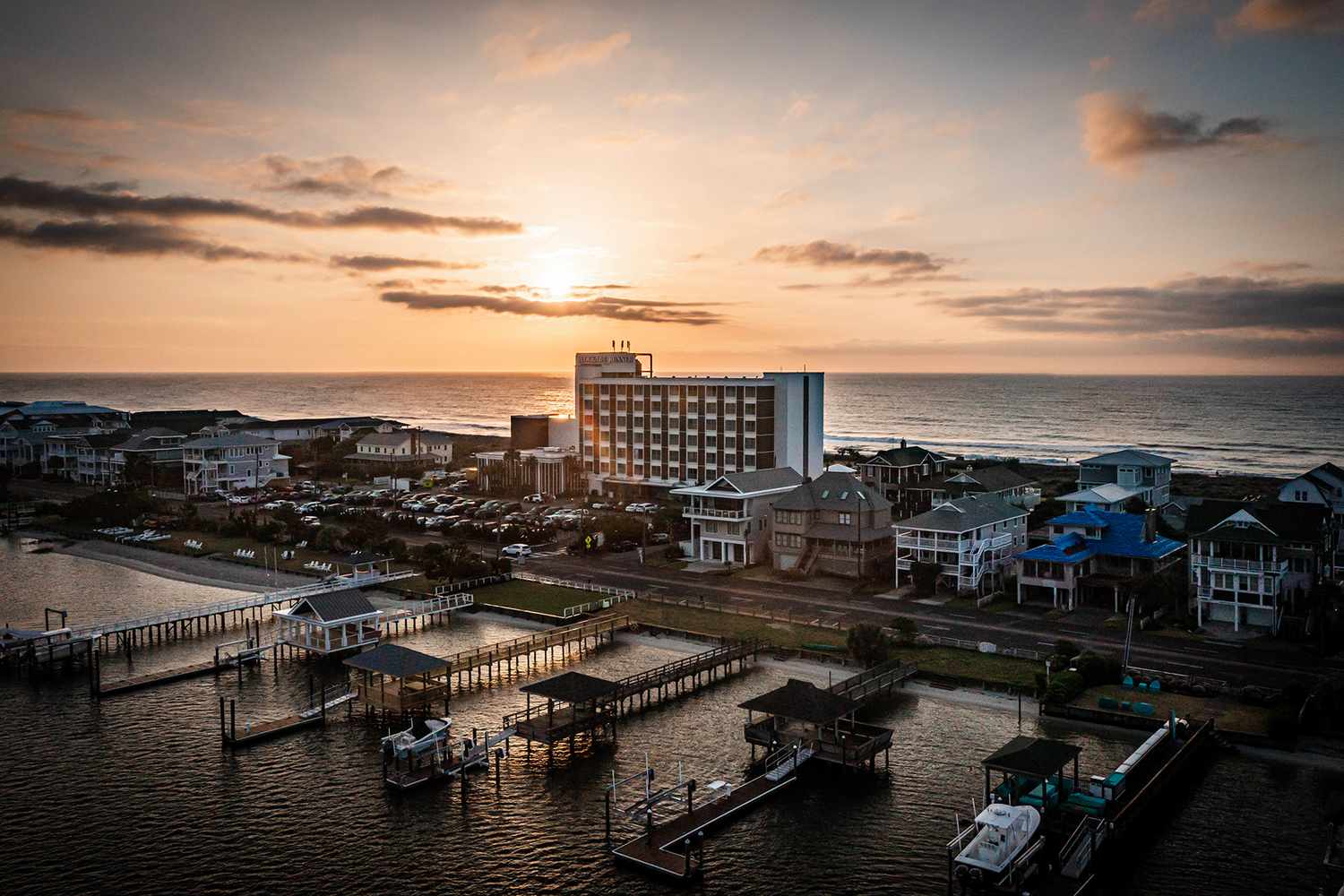 Le coucher du soleil avec des bâtiments et des quais entre la baie et la côte à Blockade Runner Resort à Wilmington
