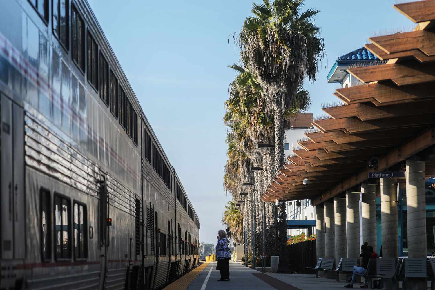 Les gens se tiennent debout alors qu'un train Amtrak est arrêté dans une gare le 9 novembre 2021 à Oceanside, en Californie.