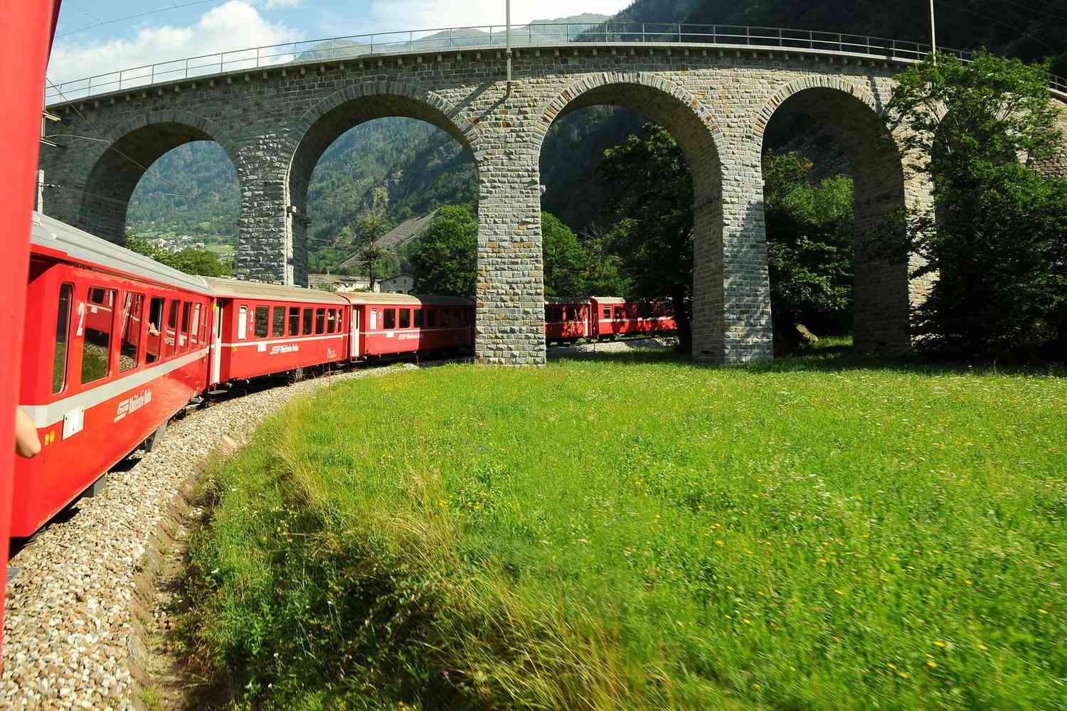Le train rouge suisse Bernina Express passe sur le viaduc de Brusio.  Il s'agit d'un pont de pierre hélicoïdal spectaculaire qui s'intègre dans le paysage environnant et est situé sur la voie ferrée de la Bernina non loin de la gare de Brusio dans le canton des Grisons, en Italie.