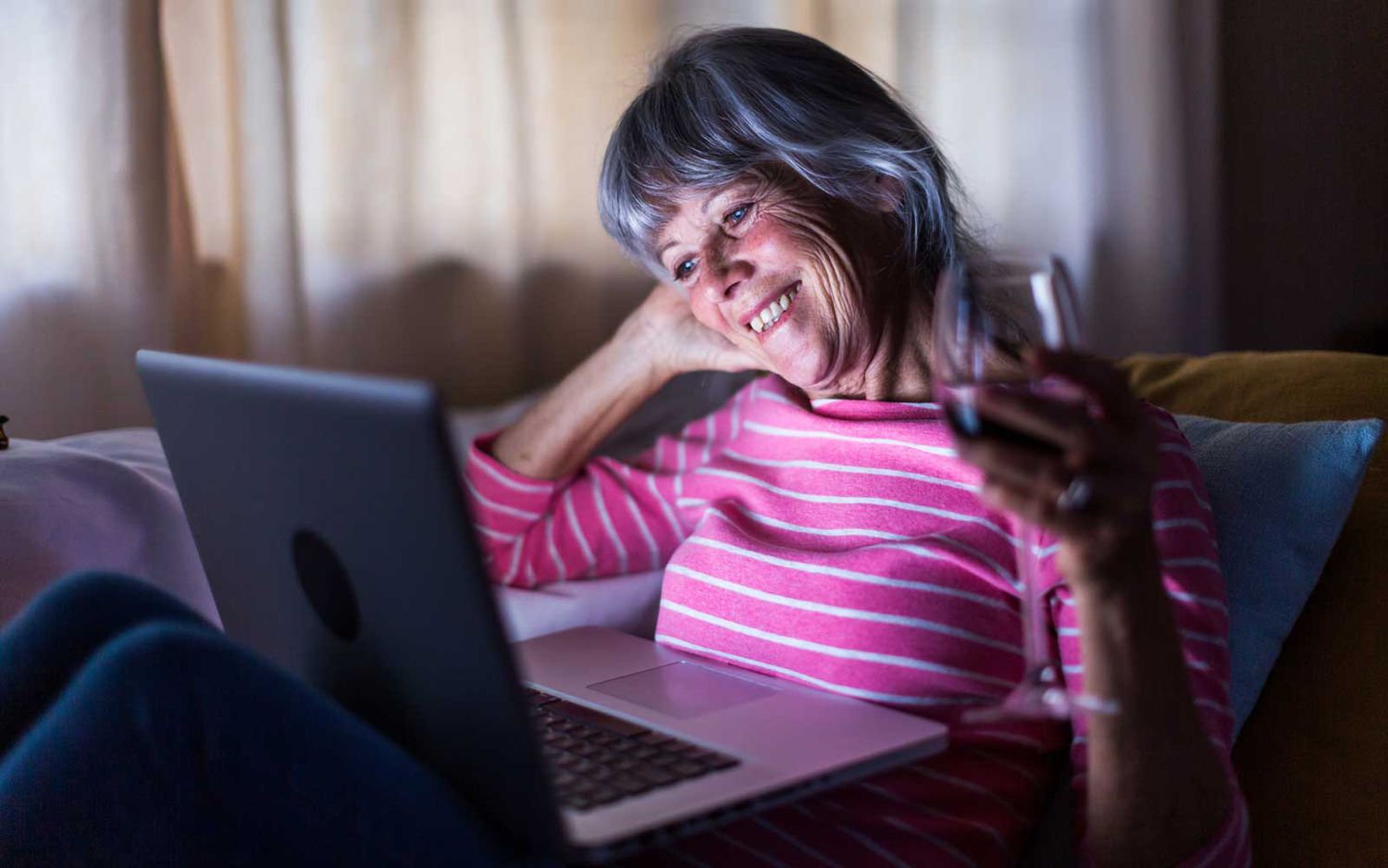 Senior woman using laptop computer pour parler à des amis de la maison