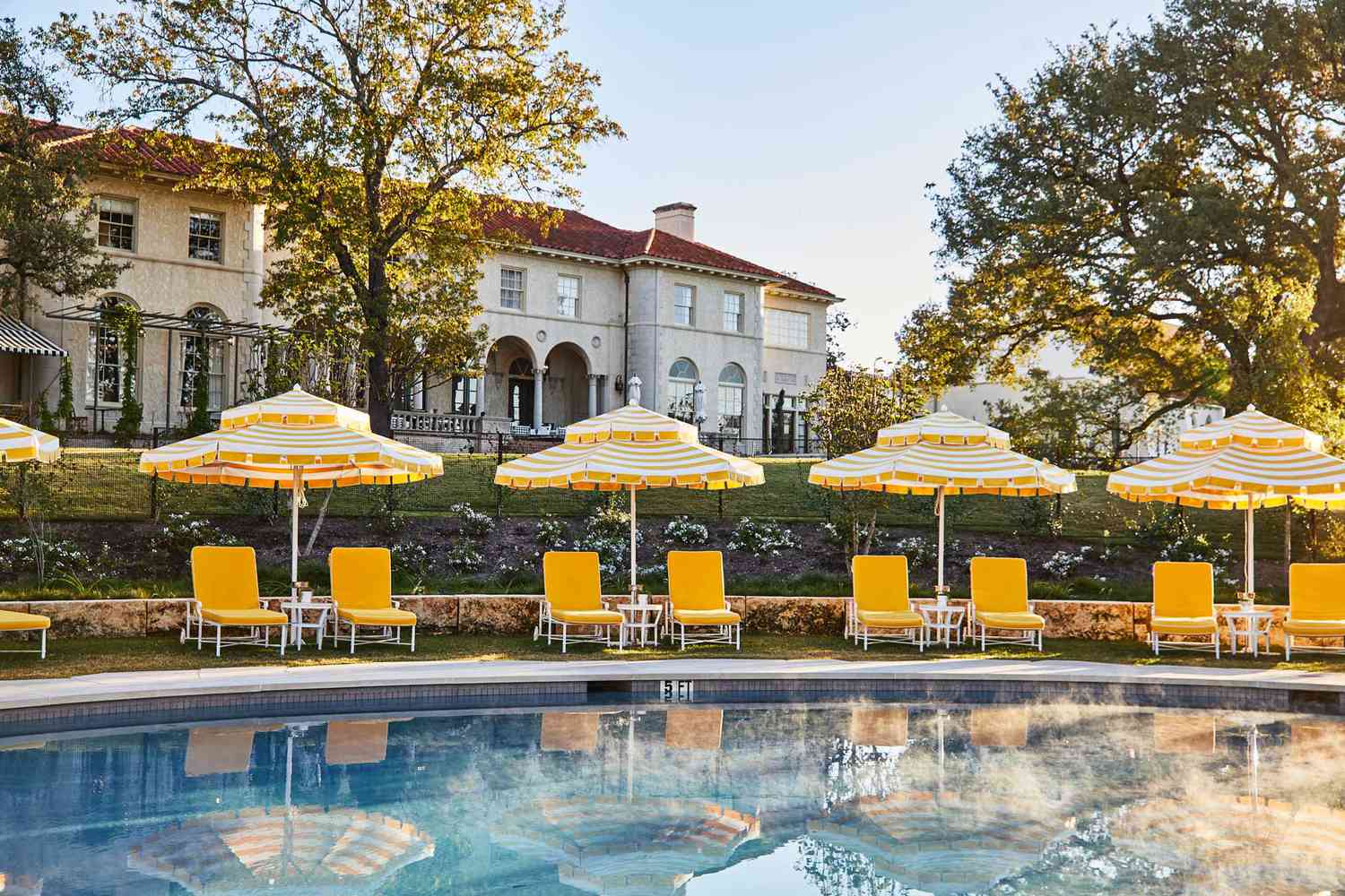 Piscine avec chaises et parasols jaunes au Commodore Perry Estate, Auberge Resorts Collection